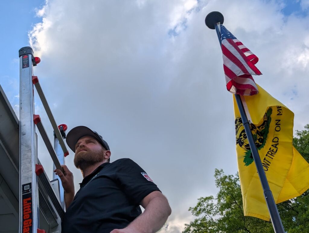 Man on ladder insepcting siding for Brody Allen Exteiors.