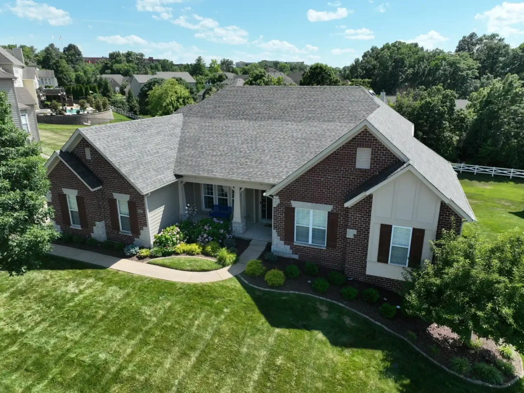 Aerial view of a modern home in Lake St. Louis with a new roof, green lawn, and well-maintained landscaping.