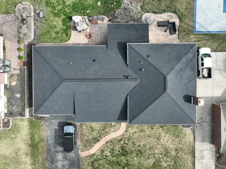 Top-down view of a dark gray shingled roof on a home in Grantwood Village, showing detailed roof layout and surrounding driveway and yard.