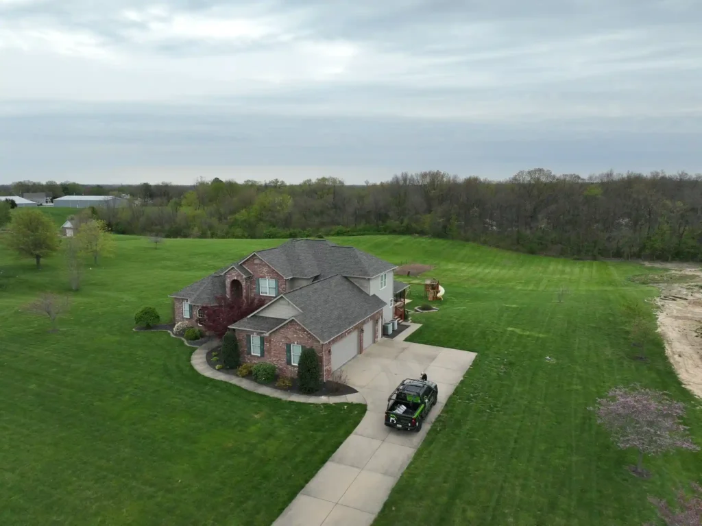 A spacious home in Wentzville, surrounded by a lush green lawn, showcasing storm damage roof repair services.
